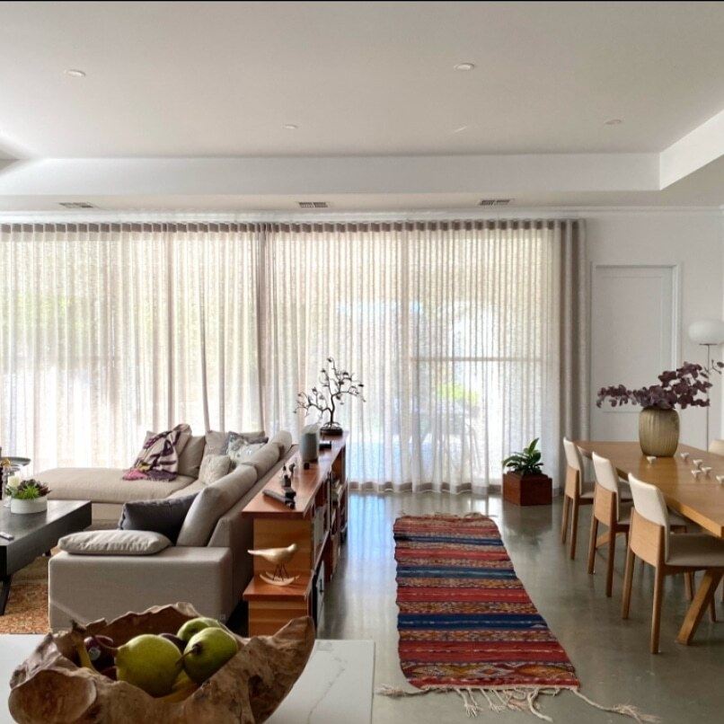 Ceiling-mounted sheer curtains along the glass doors of an open-plan living and dining room