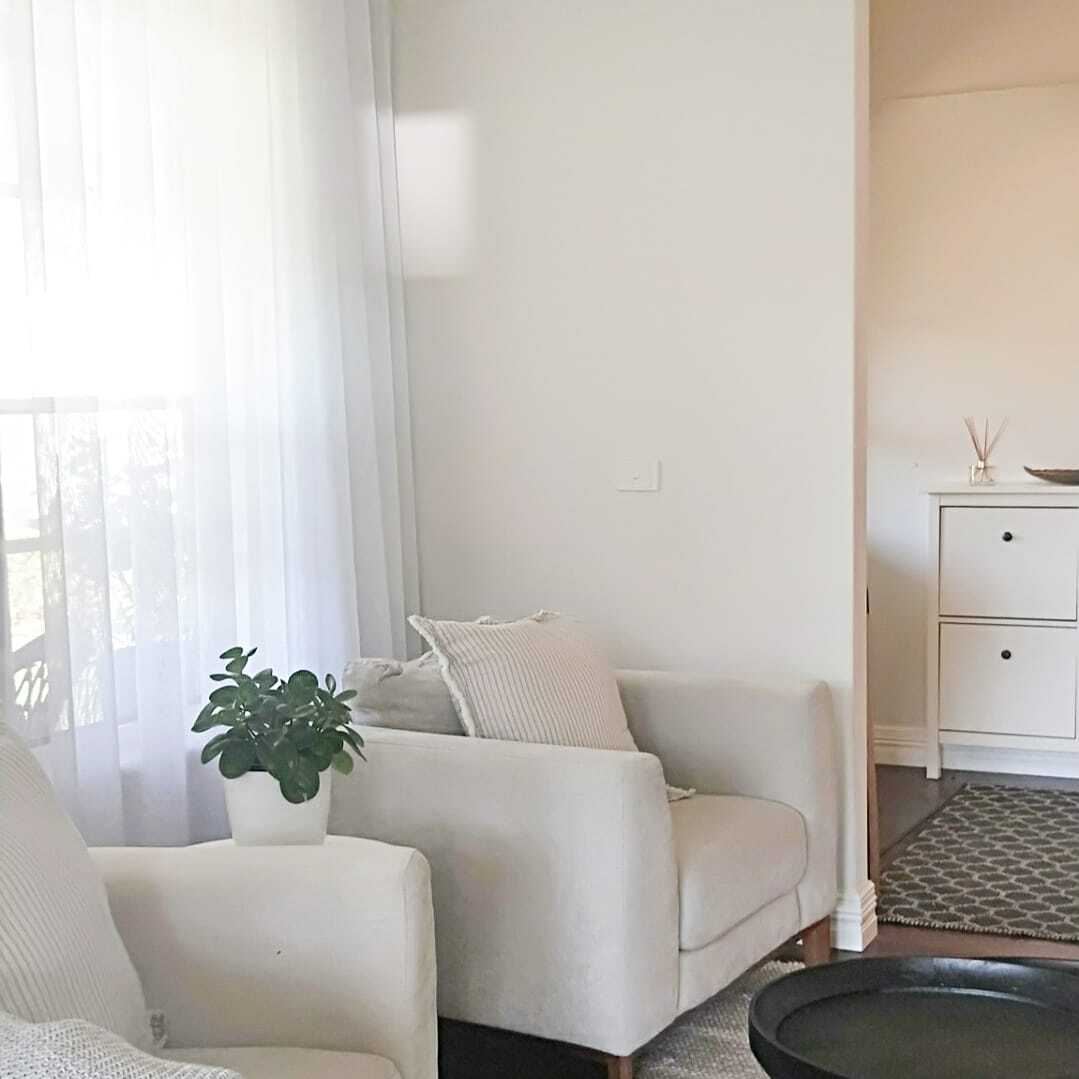White sheer curtains beside a cream armchair